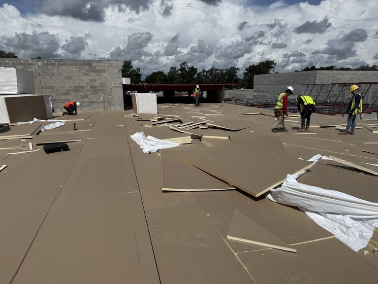 Roofers installing tapered insulation boards on a commercial flat roof before TPO membrane in Leesburg, FL