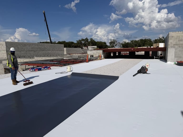 Fully adhered TPO membrane sheet being rolled into place on a commercial flat roof under construction in Leesburg, FL