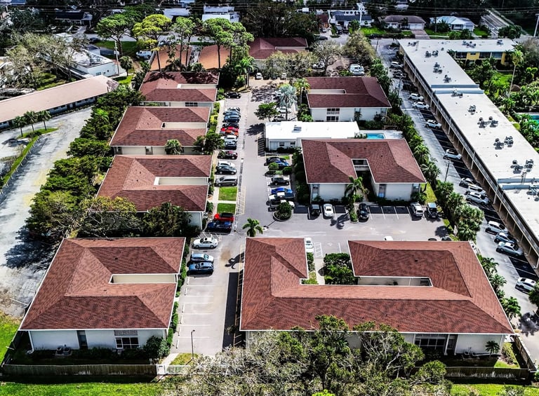 Aerial view of a condo community with red-brown architectural shingle roofs on multiple two-story buildings