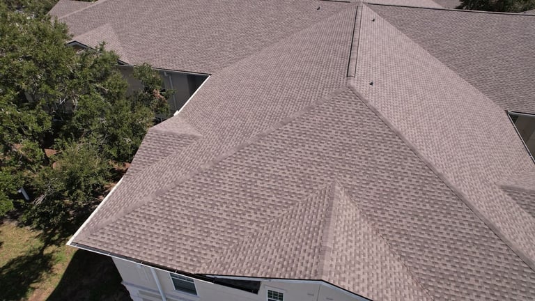 Close drone view of new architectural shingles, hip ridge caps and roof vents on an assisted living building