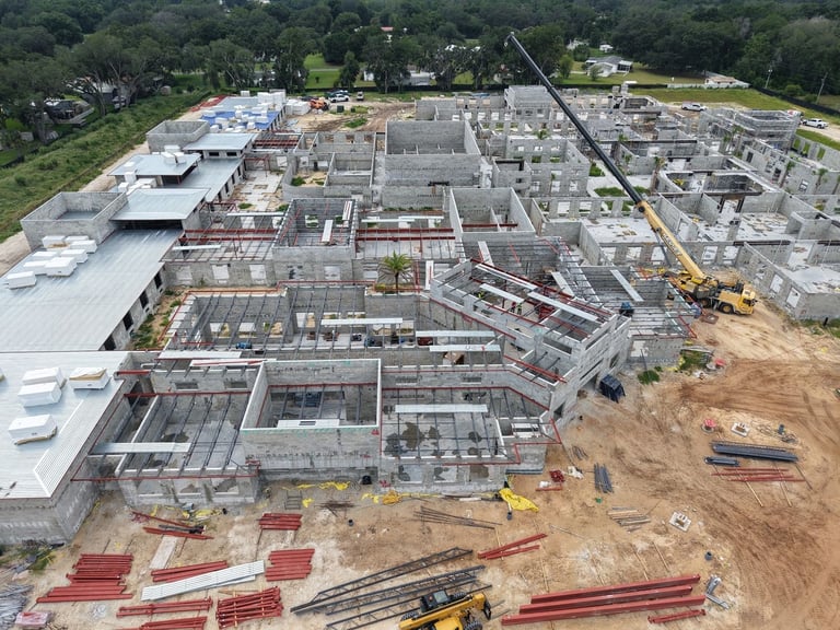 Aerial view of a large commercial building under construction in Leesburg, FL, with metal roof deck and insulation staged