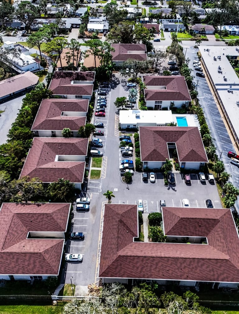 Overhead view of red-brown hip shingle roofs on a condo complex with a community pool
