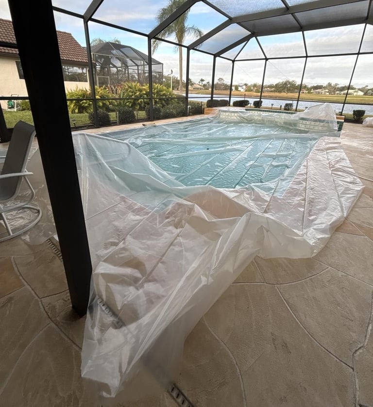 Swimming pool inside a screened enclosure covered with plastic sheeting to keep roofing debris out