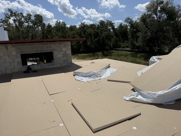 Close-up of insulation boards secured with fastener plates on a commercial flat roof prior to TPO installation