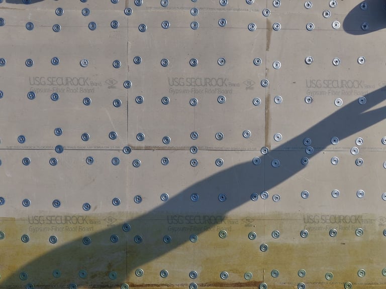 Close-up of cover board fastened with metal plates on a flat roof before the TPO membrane goes on