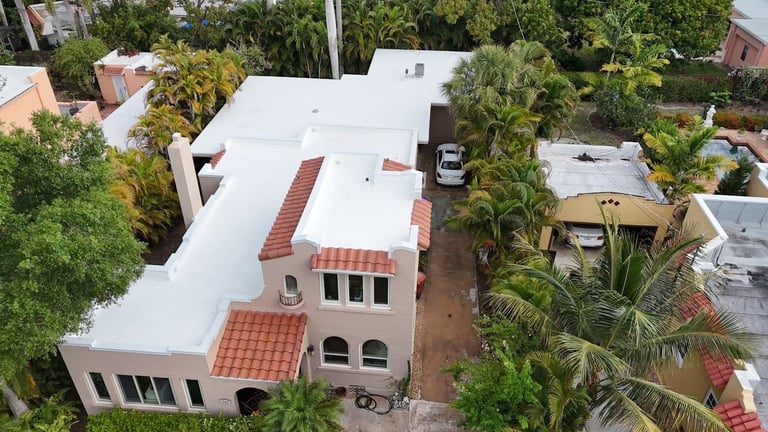 Drone view of a stucco home's completed white flat roof system with clay tile sections and parapet walls