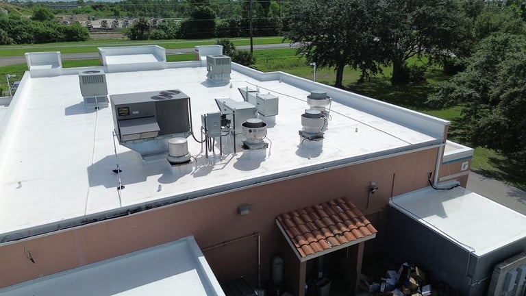 New white single-ply flat roof membrane around rooftop HVAC and kitchen exhaust equipment on a restaurant