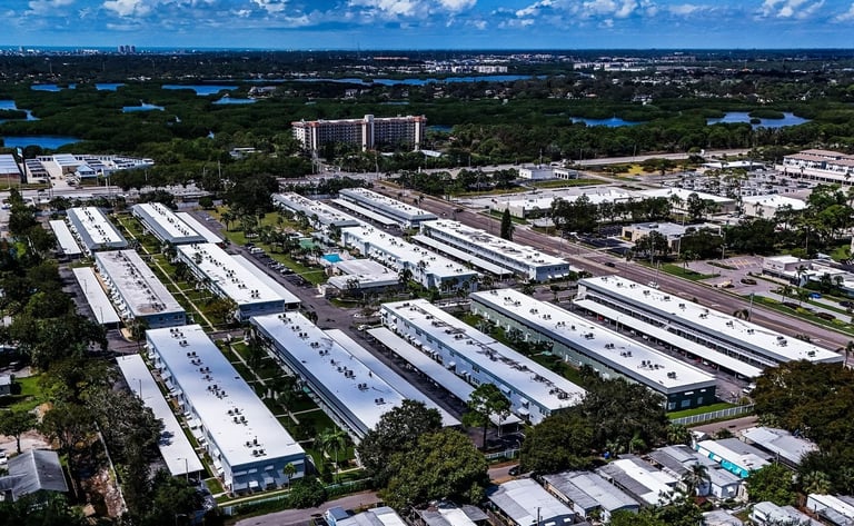Aerial view of a residential condo community with low-rise buildings and white TPO flat roofs