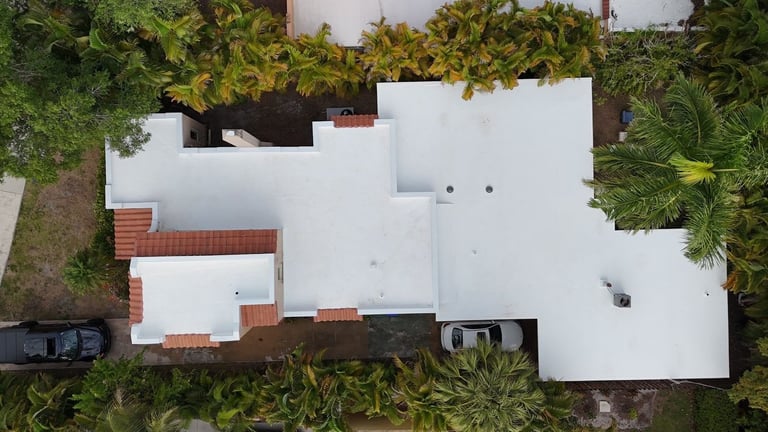 Top-down aerial of a multi-level white flat roof with clay tile accent sections on a residential home