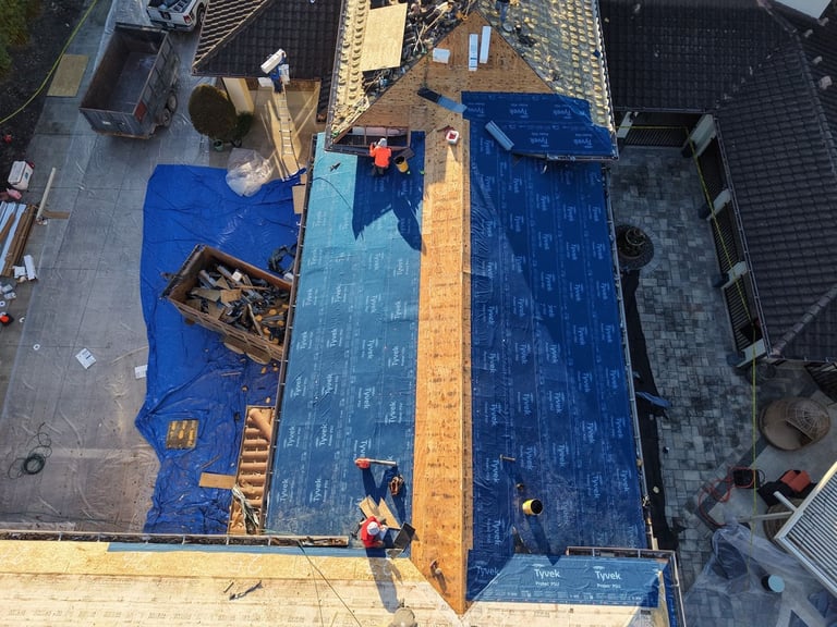 Overhead view of crew installing blue self-adhered tile underlayment over new plywood roof decking
