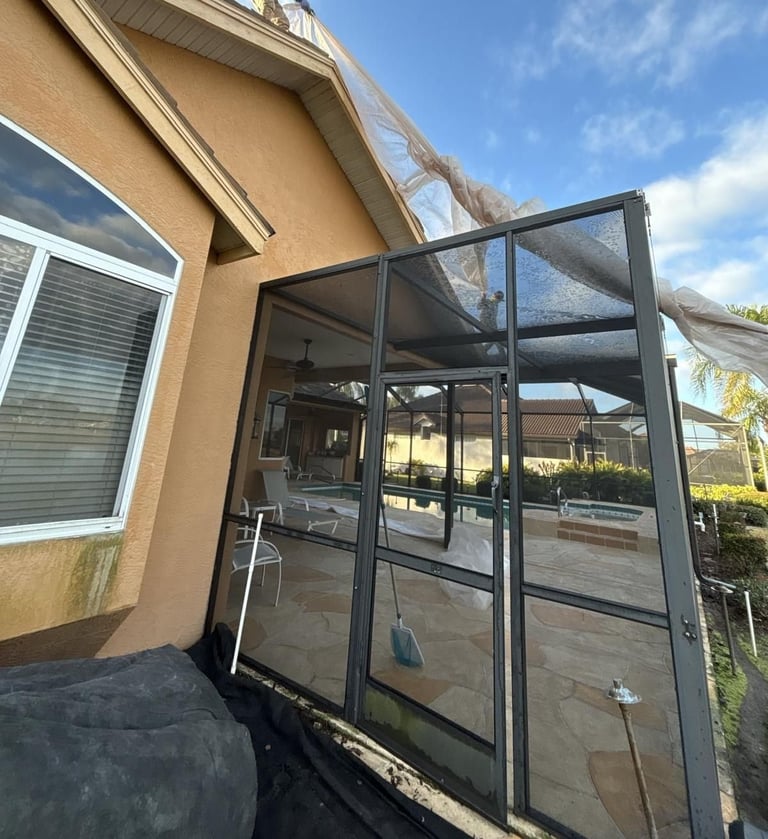 Plastic sheeting draped from the roof over a screened pool enclosure to catch debris during a tile reroof