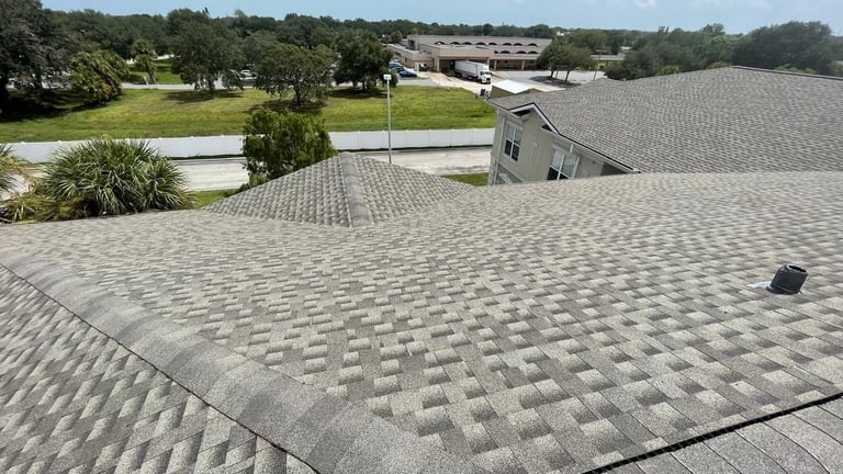 Close-up of new architectural shingles with hip ridge caps and a roof vent on a commercial care facility