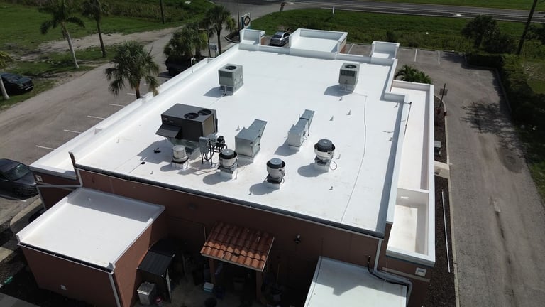 Elevated view of a restaurant's new white flat roof with parapets, rooftop units and lower roof sections