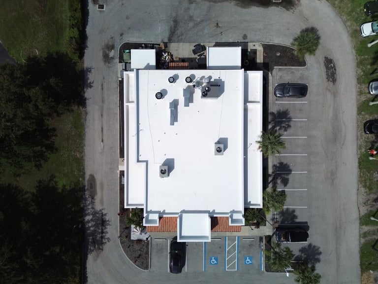 Overhead drone view of a restaurant's completed white membrane flat roof with HVAC units and parapet walls