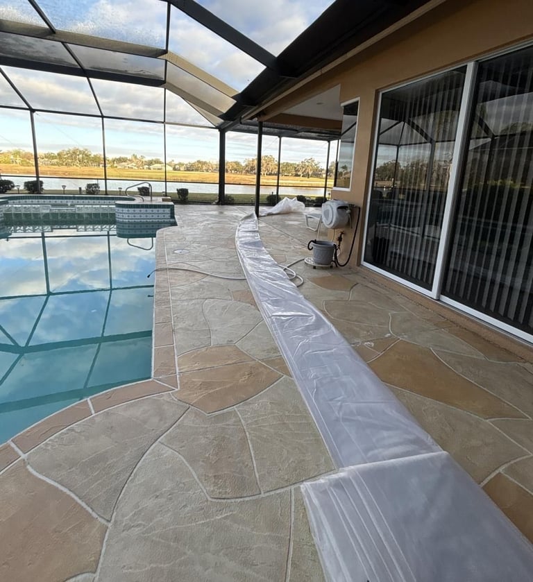 Pool deck protected with plastic sheeting along the pool edge under a screened lanai during roof replacement