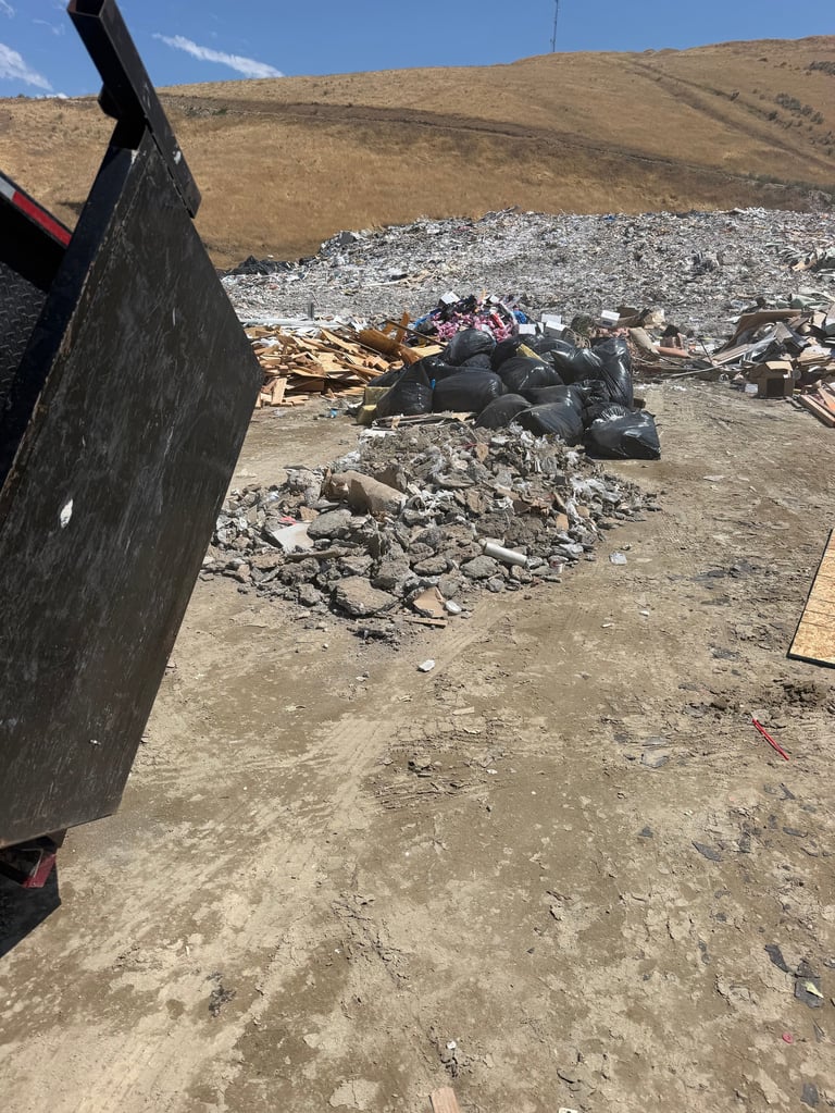 Construction debris and rubble scattered on barren hillside with brown earth and sparse vegetation.