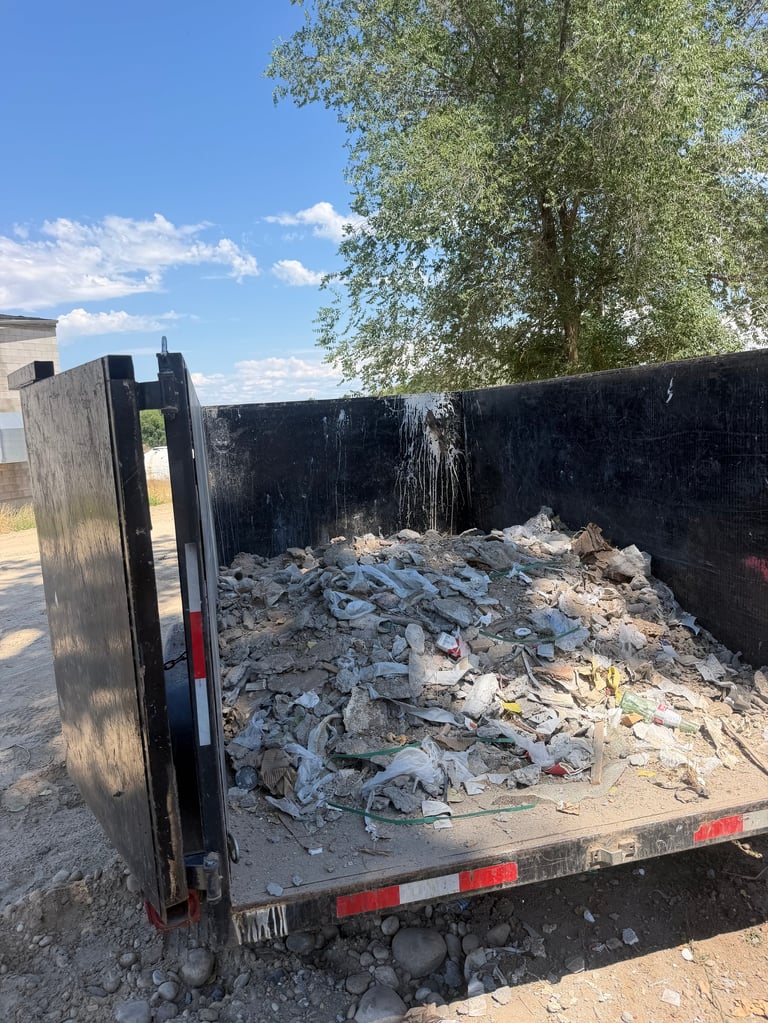 Open truck bed filled with construction debris and rubble under bright blue sky.