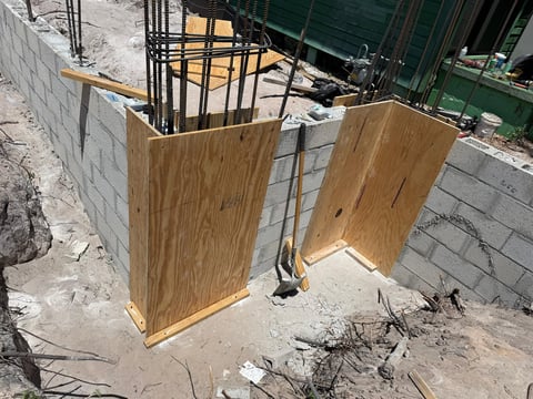 Construction site with wooden plywood panels enclosing steel reinforcement rebar structure on concrete block foundation