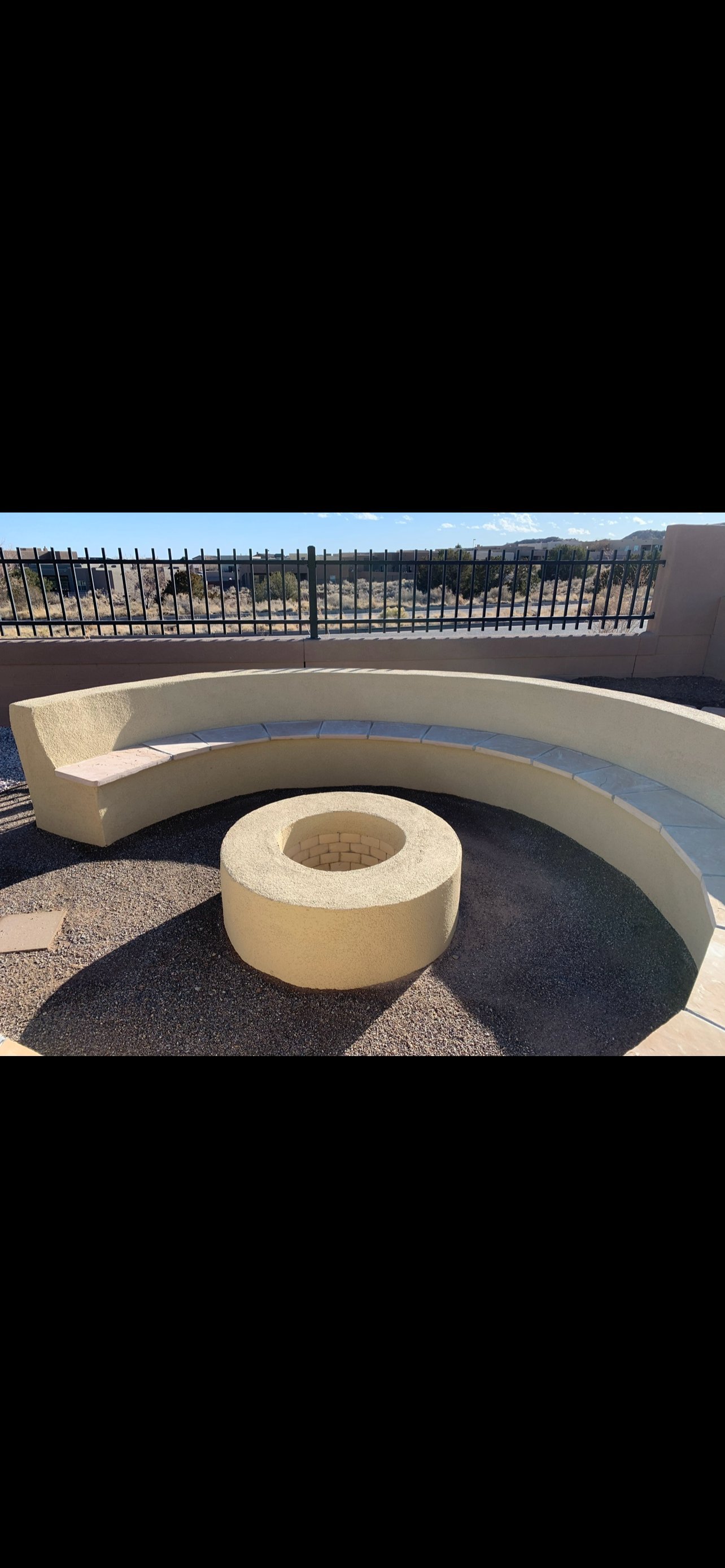 Modern curved concrete bench and circular fire pit on a rooftop with mountain views