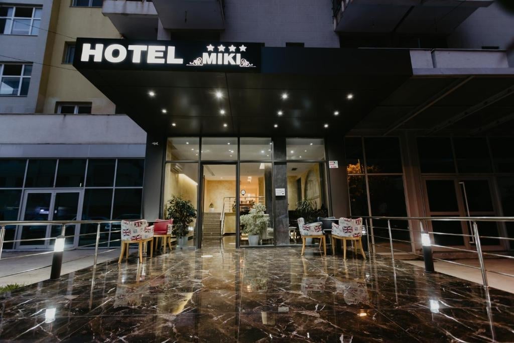 Modern hotel entrance with illuminated black awning, glass doors, and wet pavement at night