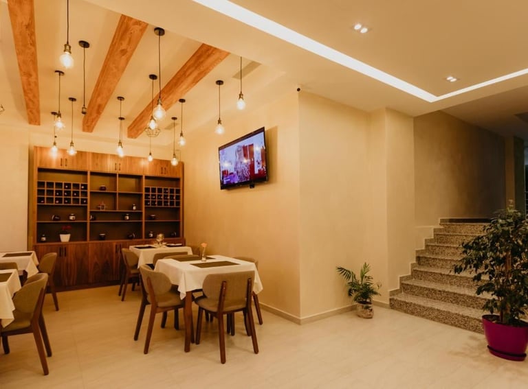 Modern dining room with wooden beams, pendant lights, dining tables, wooden cabinetry, wall-mounted TV, and staircase entrance.