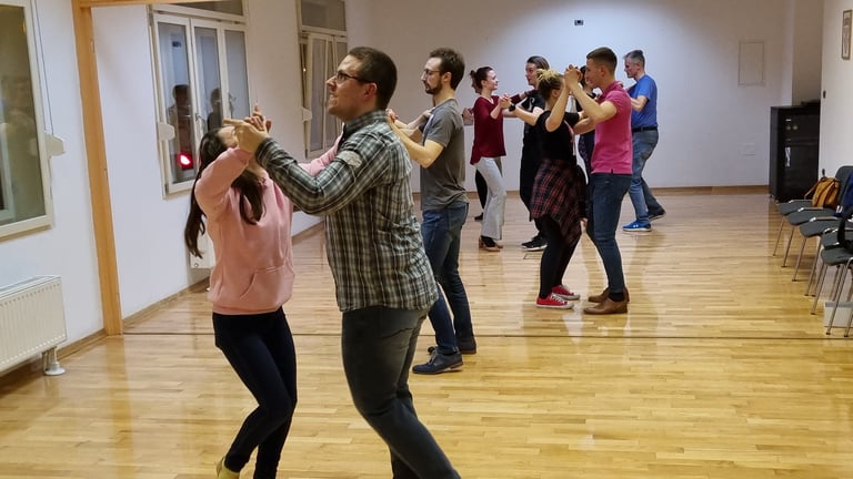 Grupa polaznika pleše zajedno na plesnom tečaju u svijetloj dvorani s drvenim podom Plesne škole Banderillas
