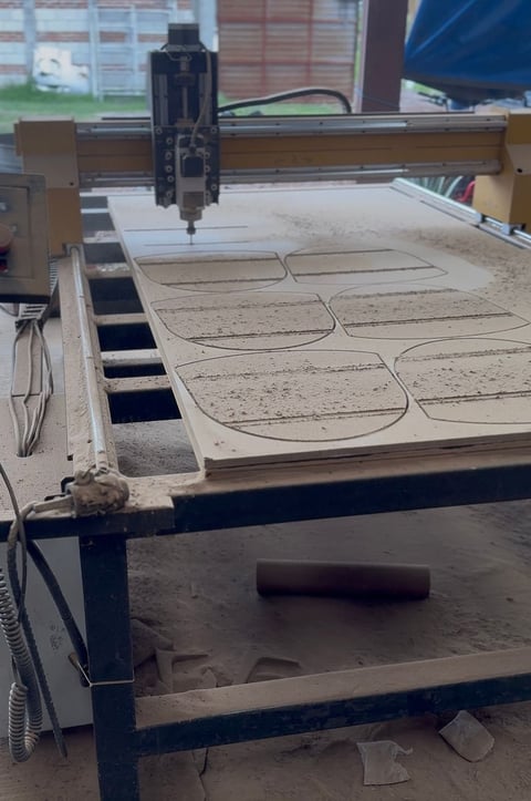 CNC laser cutter engraving curved designs on large wooden panels in a workshop