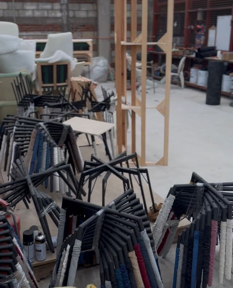 Furniture showroom with stacked black and metal chairs in foreground, wooden door frame, and white seating displayed in background