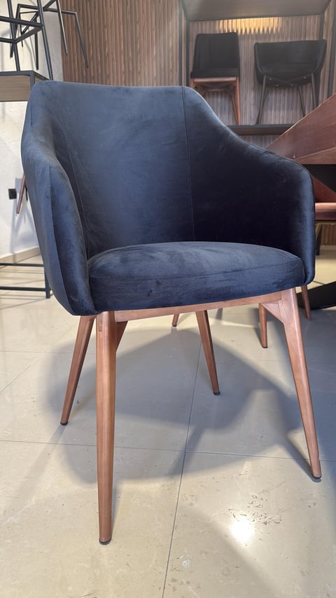 Modern blue upholstered accent chair with wooden legs displayed in a furniture showroom