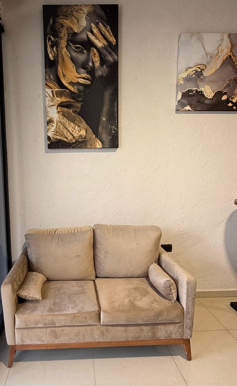 Beige upholstered loveseat with wooden legs in a living room with modern artwork on white walls