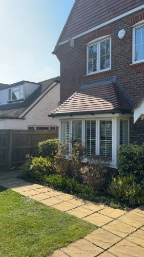 Modern brick home extension with pitched roof, white-framed windows, landscaped garden and stone patio pathway