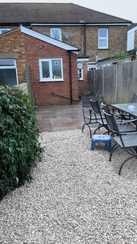 Brick home exterior with patio area featuring metal chairs, climbing ivy, and gravel courtyard