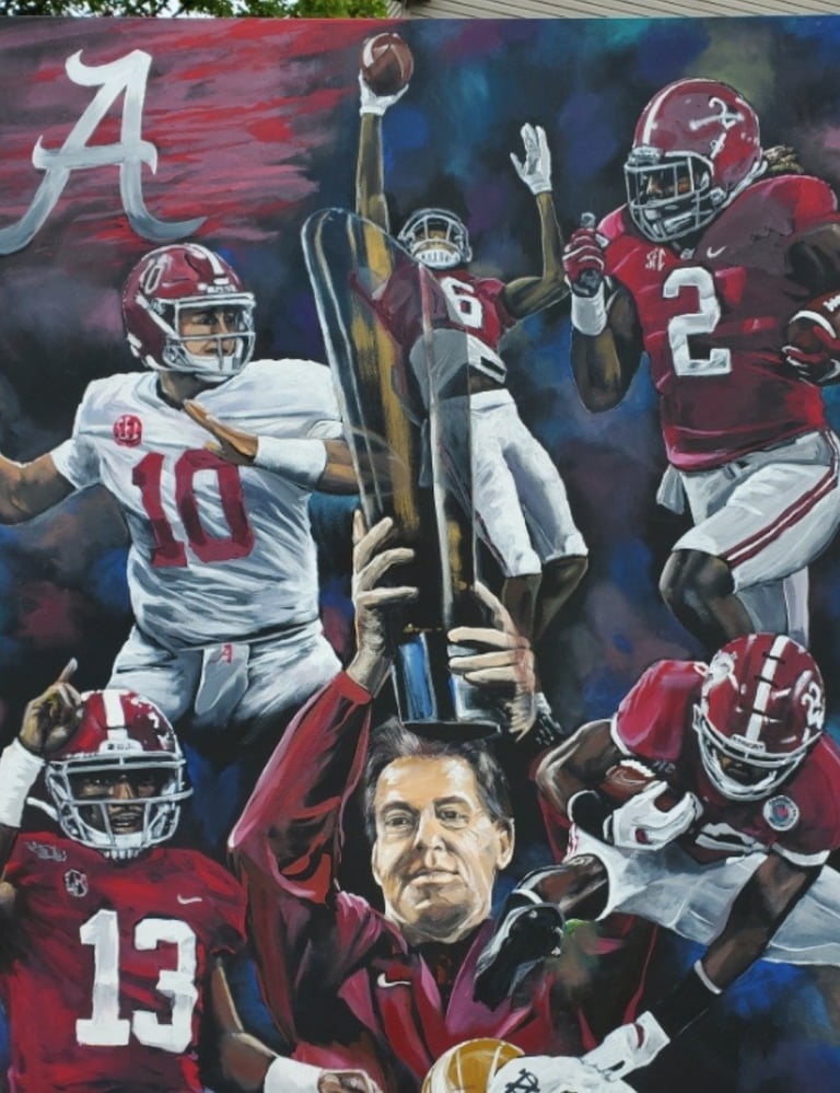Mural depicting Alabama football coach with players in crimson jerseys, Alabama logo, and football imagery