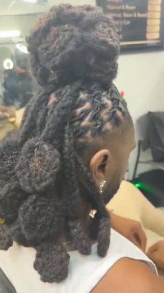 Back view of a person with thick dreadlocks styled and held together with beads and ornaments