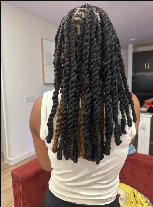Person with long black two-strand twists with caramel highlights, viewed from behind, wearing a white sleeveless top