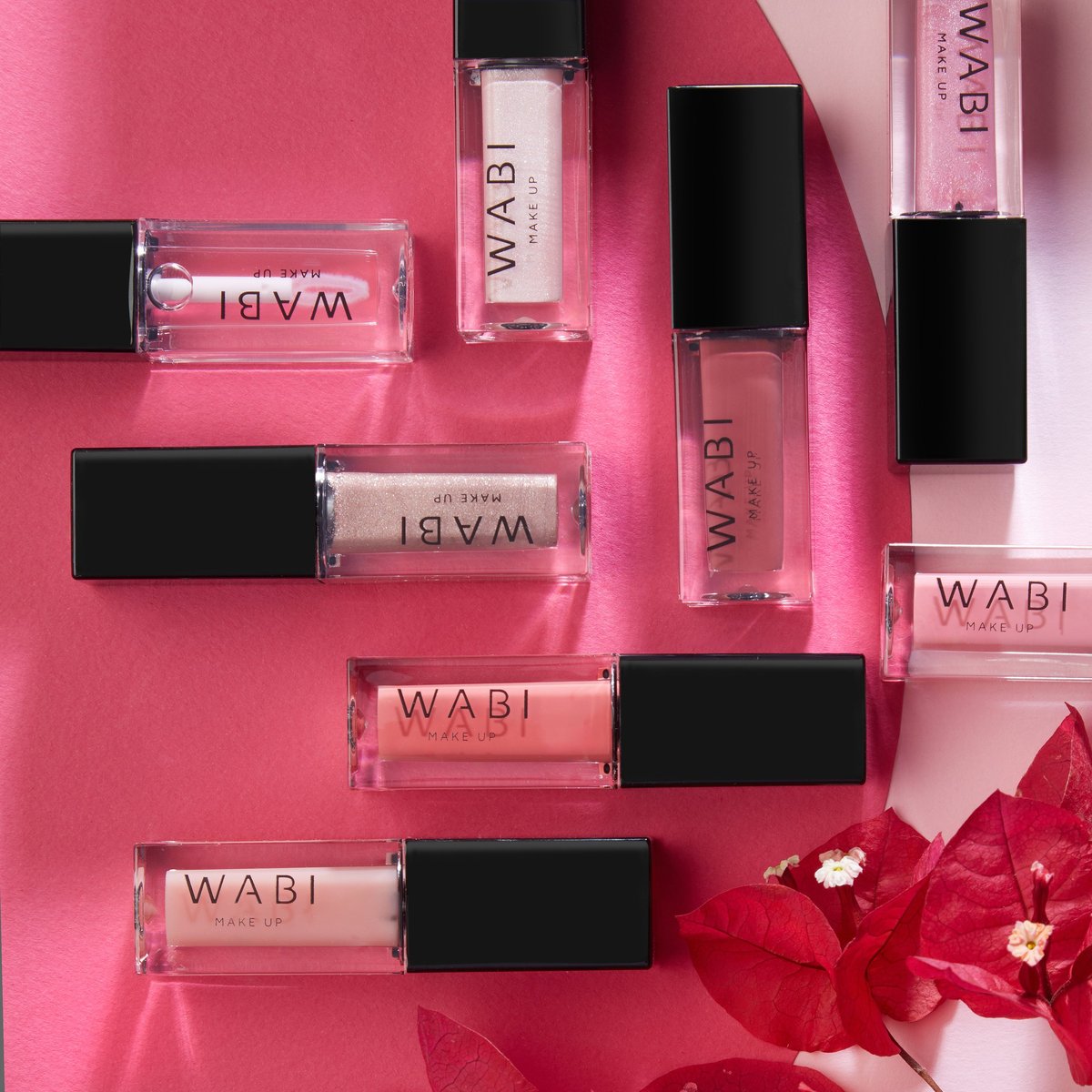 WABI cosmetics makeup products arranged on pink background with red flowers