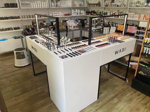 Beauty store display counter showing cosmetic brushes and makeup products with shelves of inventory in background
