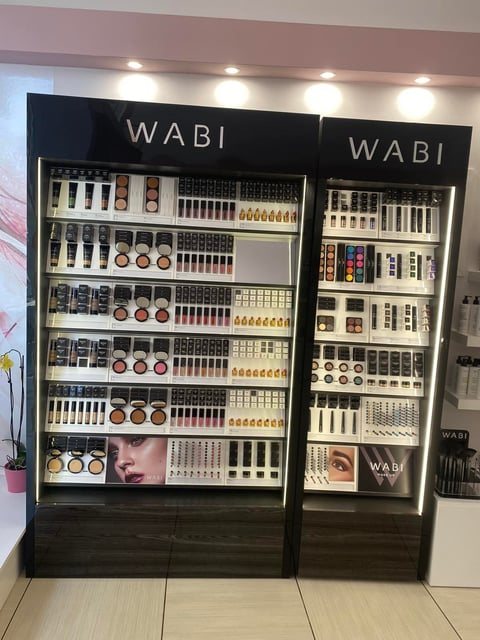 WABI cosmetics display stand with makeup products including lipsticks, eyeshadows, and brushes organized on illuminated shelves