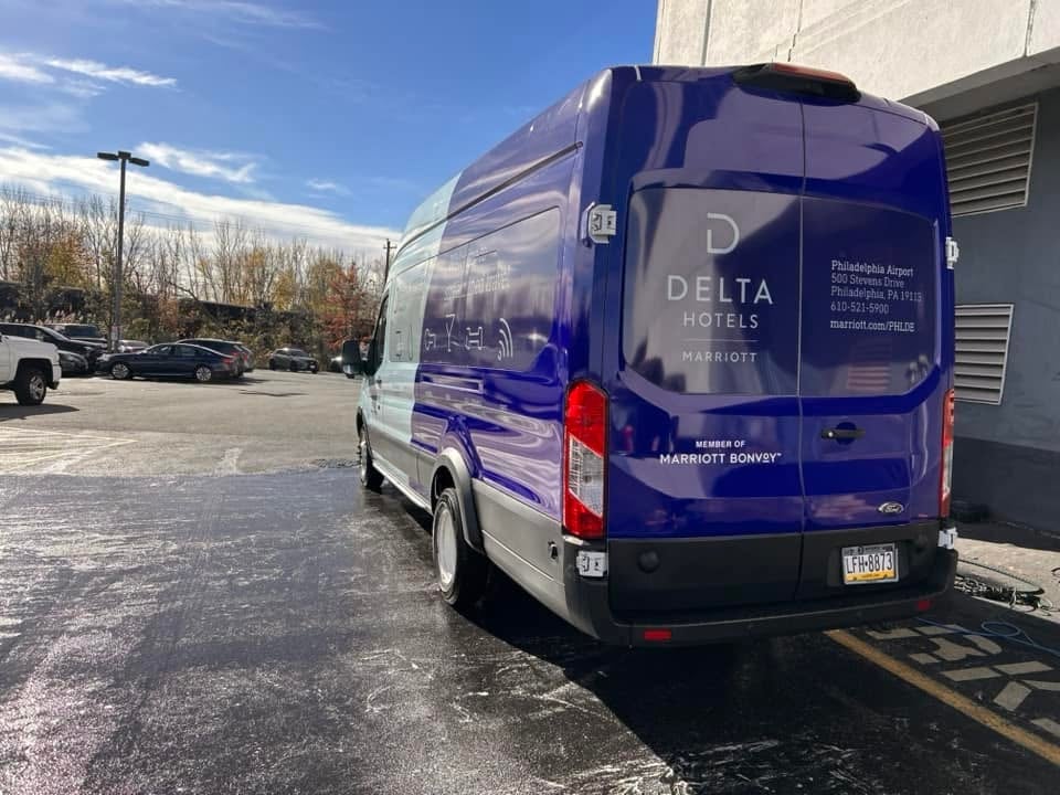 Blue Delta Hotels shuttle van parked in a lot on a sunny day