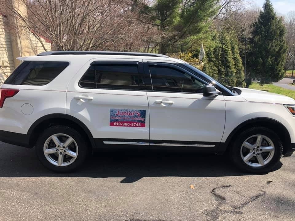 White SUV with the Junior's Custom Auto Detailing magnet sign on its side, parked on a residential street