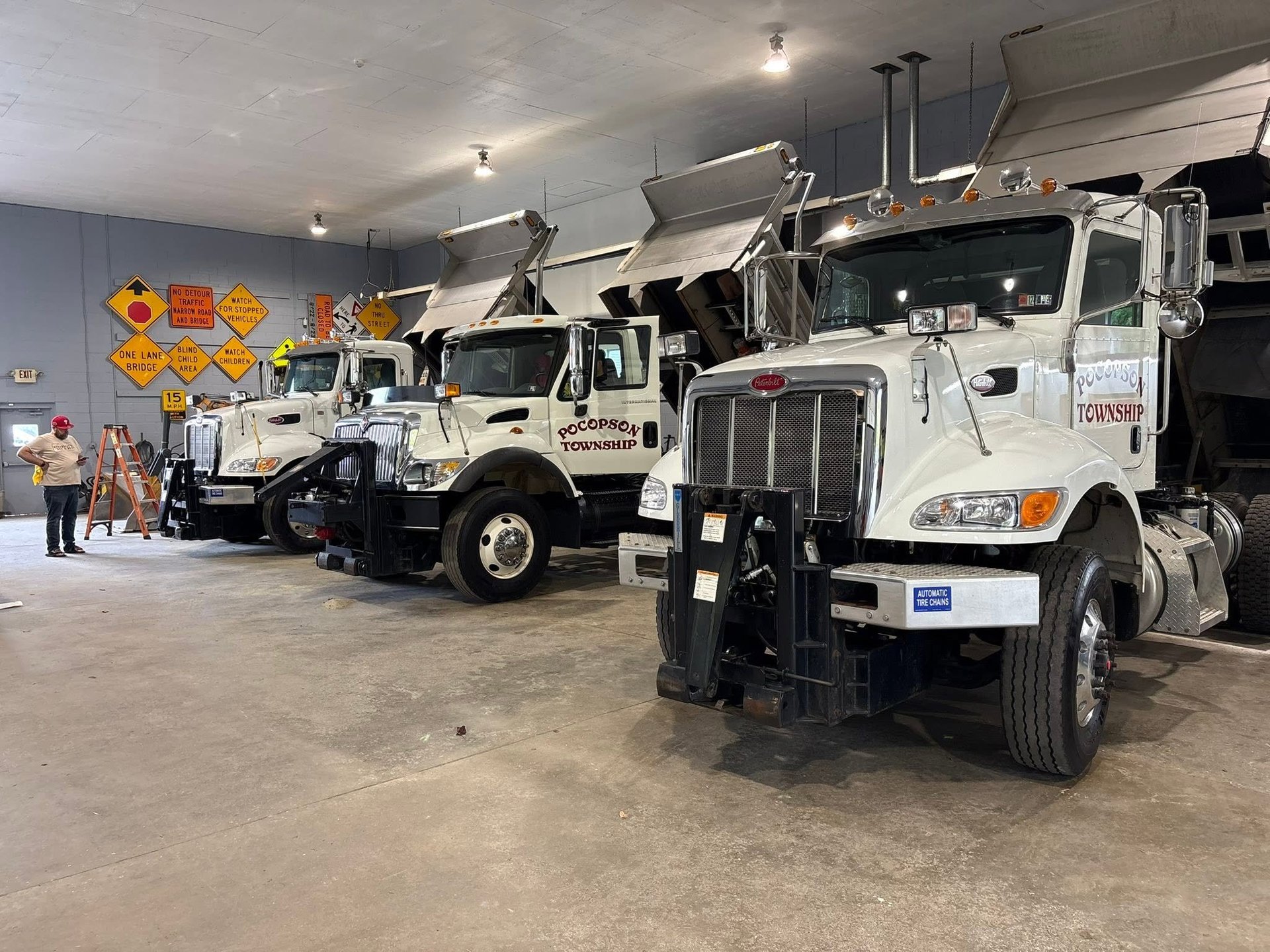 Row of white Pocopson Township utility trucks parked in an indoor garage facility with service equipment visible