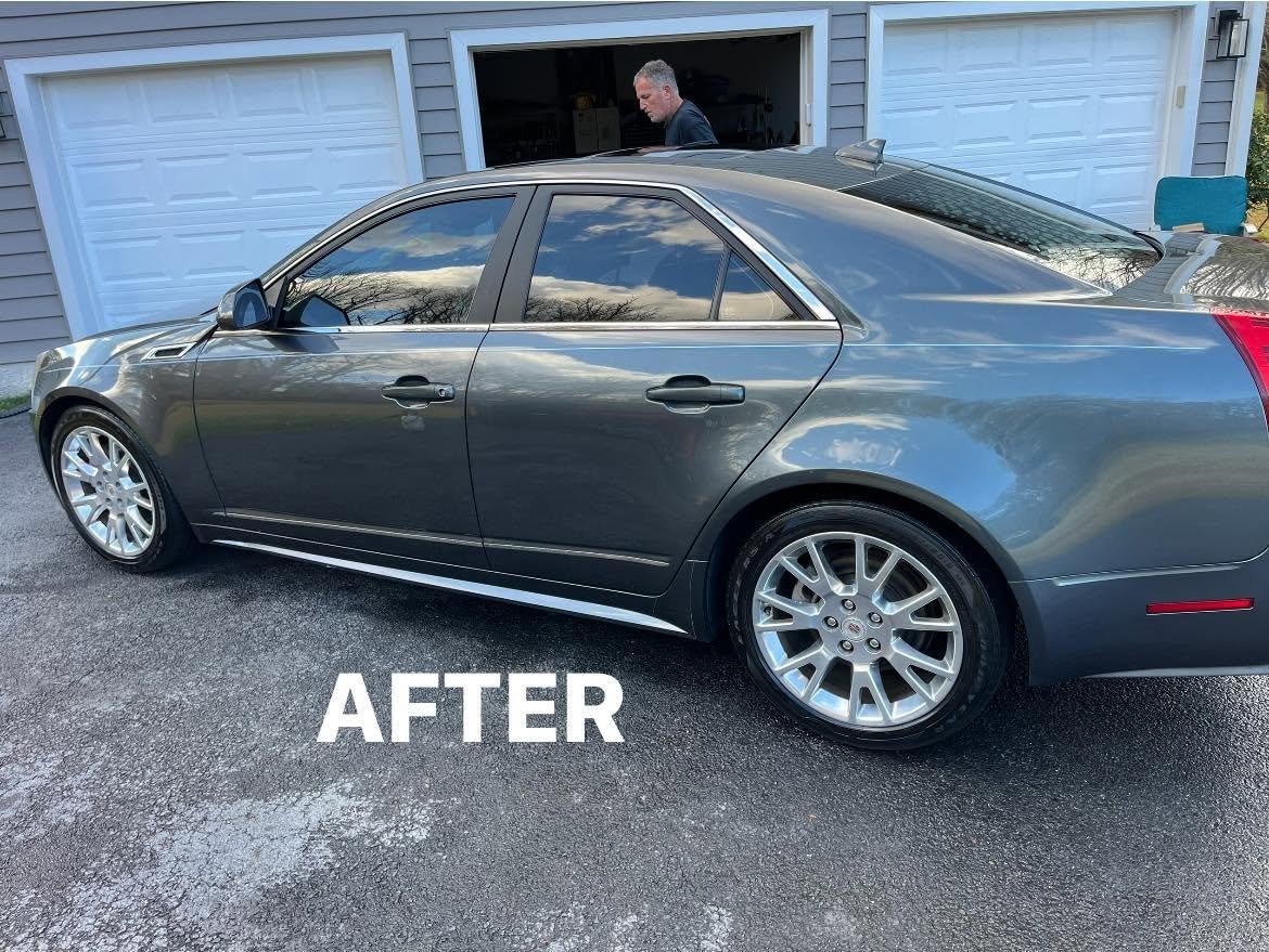 Shiny gray Cadillac sedan with polished white-wall tires parked in a driveway after a full detail