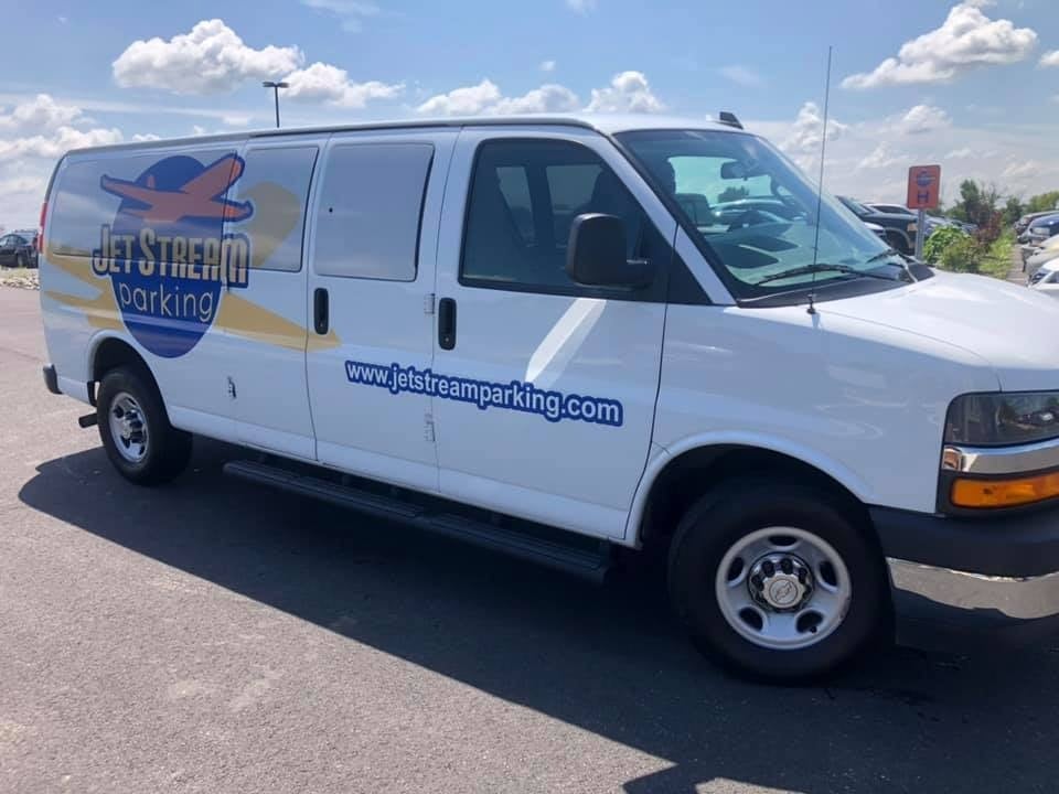 White Chevrolet cargo van with Jetstream Parking branding detailed in a lot under blue sky
