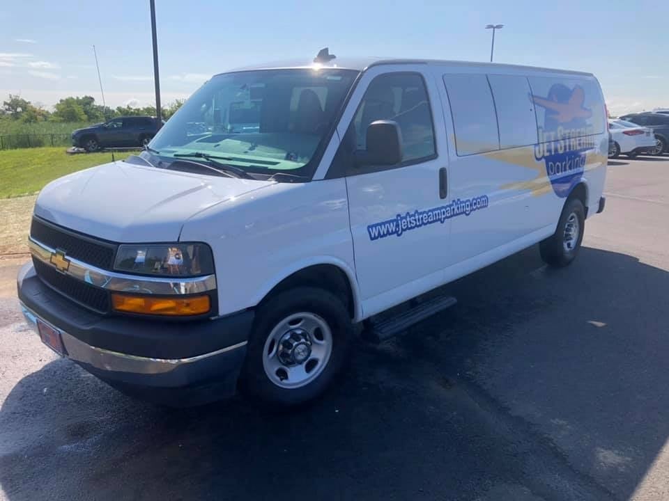 White Chevrolet cargo van with blue Jetstream text logo, freshly detailed in a sunny lot