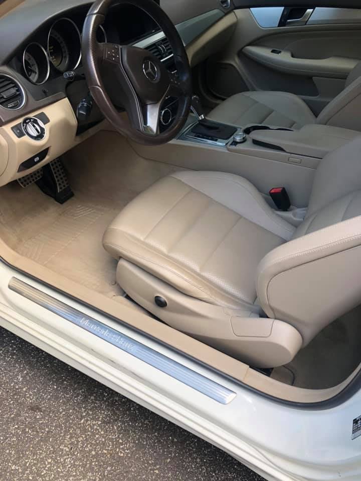 Beige leather interior of a luxury sedan after interior detailing, viewed through the open driver's door