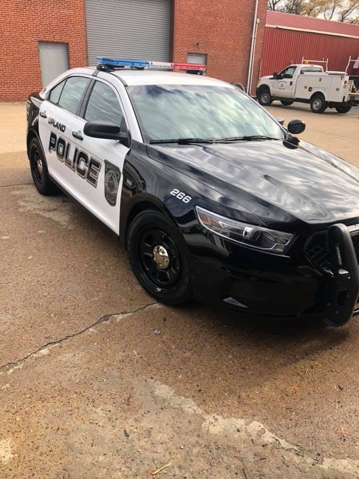 Black and white Upland Police car (unit 266) freshly detailed in front of a brick building