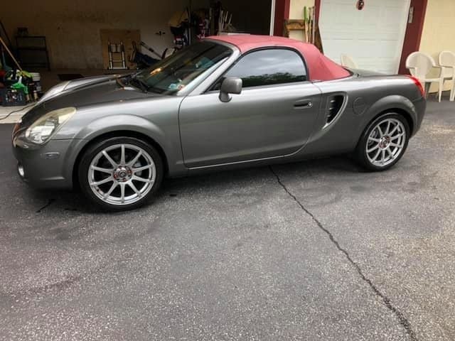 Gray and red convertible sports car with a pink hardtop parked in a driveway