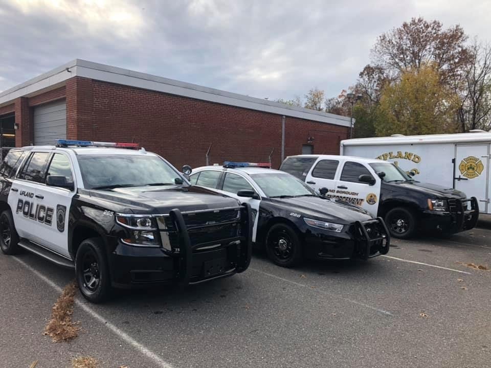 A row of Upland Police vehicles and emergency response vehicles detailed in front of a brick municipal building