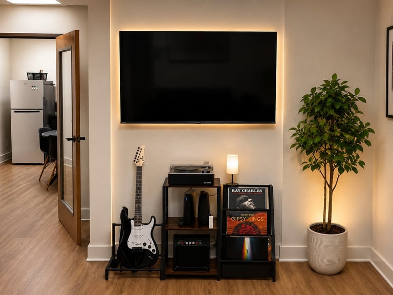 Modern living room corner with wall-mounted black screen, black electric guitar on stand, amplifier, decorative plant, and ambient lighting