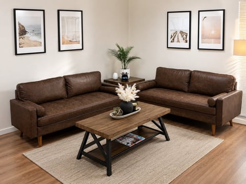Modern living room with brown leather L-shaped sectional sofa, wooden coffee table, and framed landscape artwork on cream walls